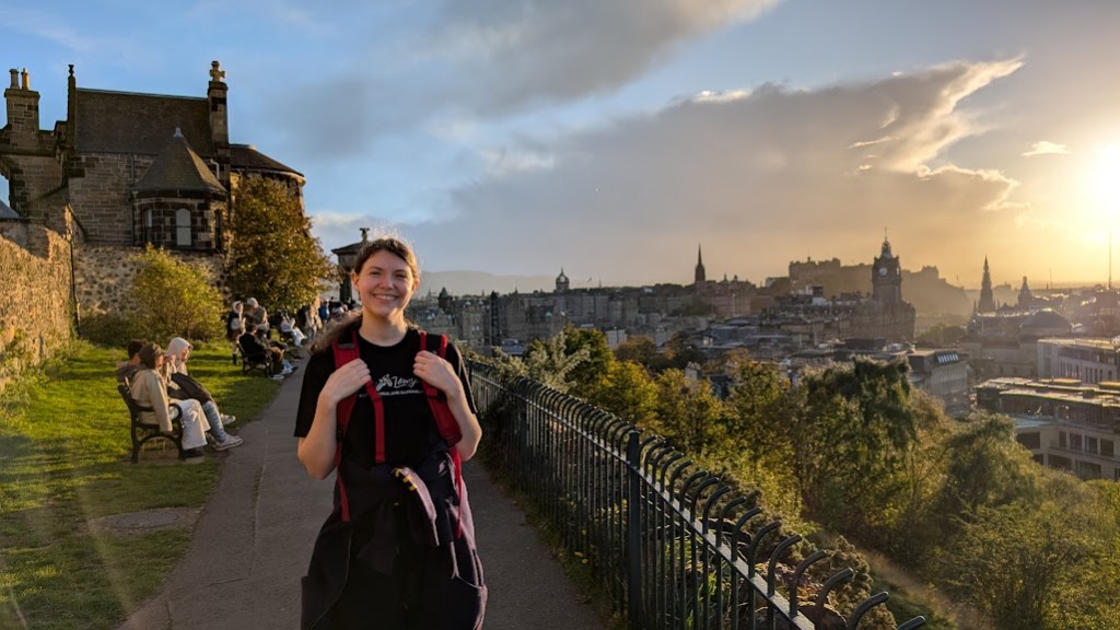 Elizabeth on Calton Hill with Edinburgh behind and the sun setting.