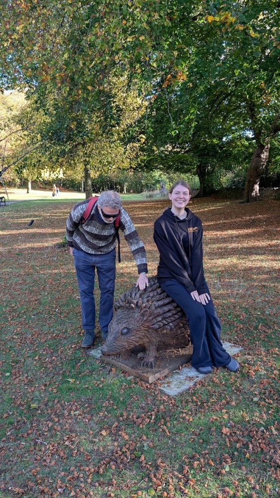 Elizabeth sitting on a hedgehog and Ben is patting it.